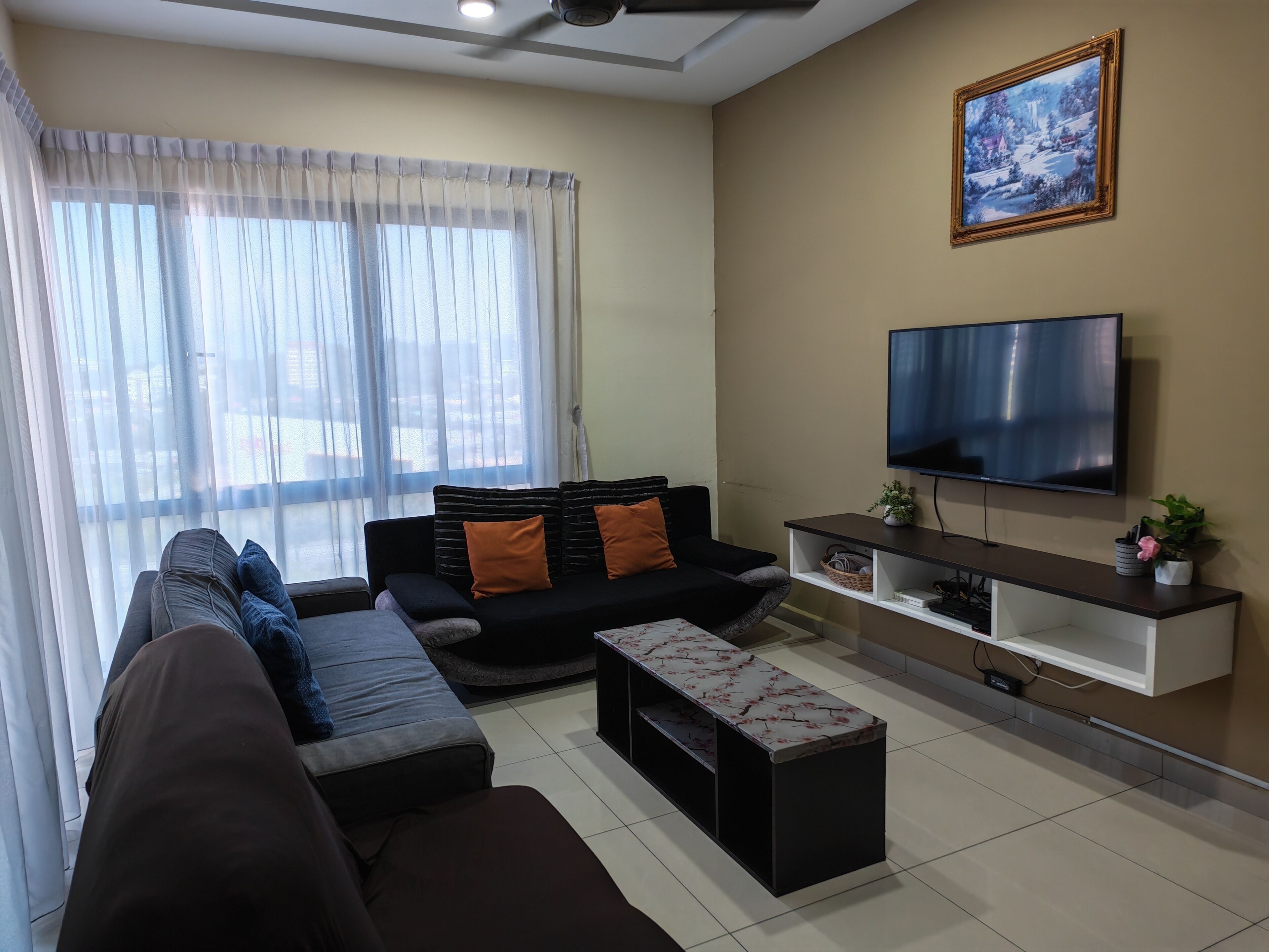 Uma sala de estar moderna com sofá, televisão e um quadro na parede.