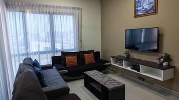 Uma sala de estar moderna com sofá, televisão e um quadro na parede.