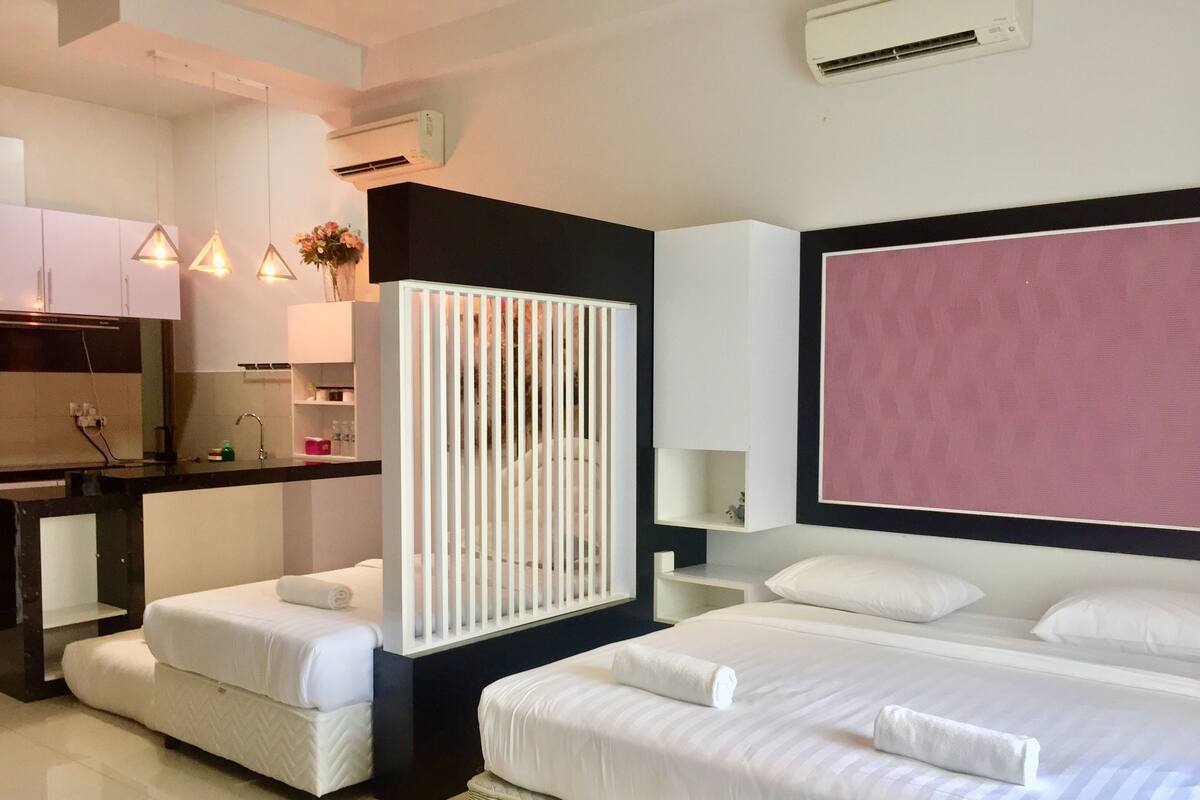 Una habitación de hotel moderna con una cama, un escritorio y una kitchenette.