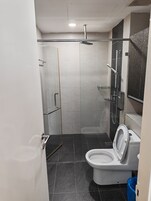 Un baño moderno con ducha, inodoro y cabina de ducha acristalada.
