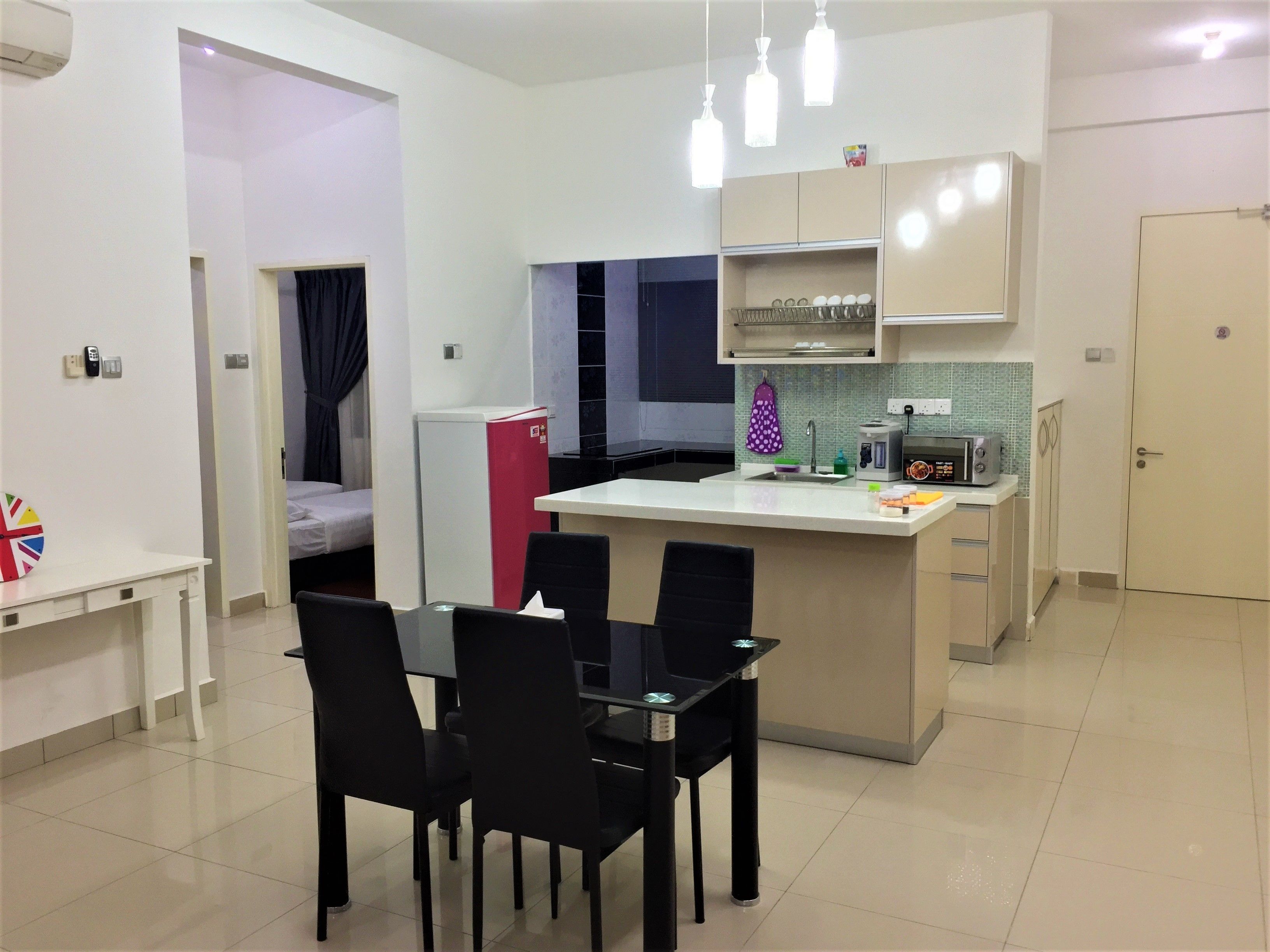 A compact kitchen with a dining area, a refrigerator, a microwave, and a small sink.
