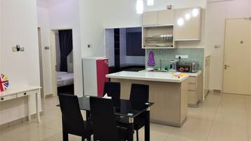 A compact kitchen with a dining area, a refrigerator, a microwave, and a small sink.
