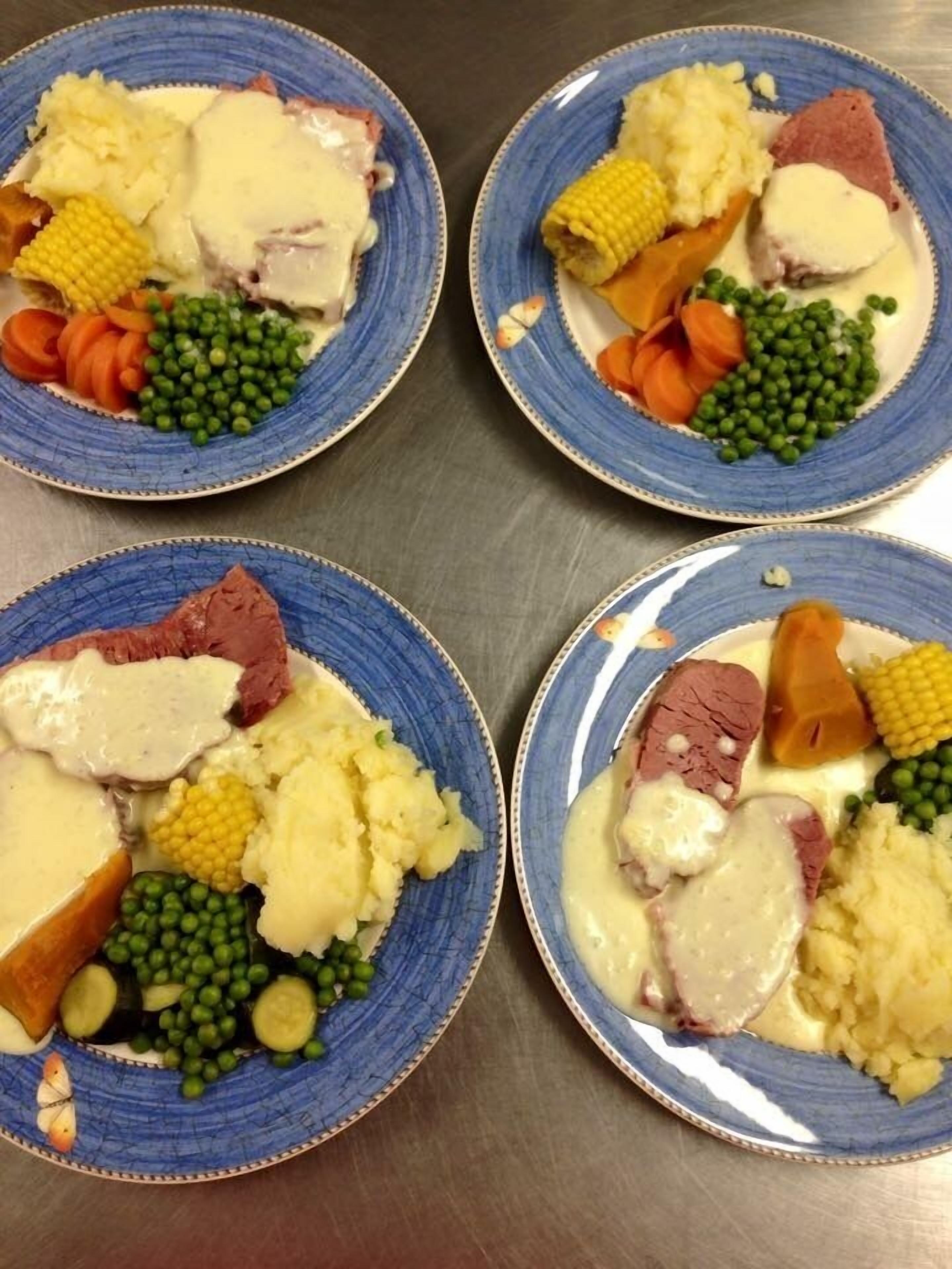 Cuatro platos de comida con diferentes verduras y carne, servidos en platos azules.