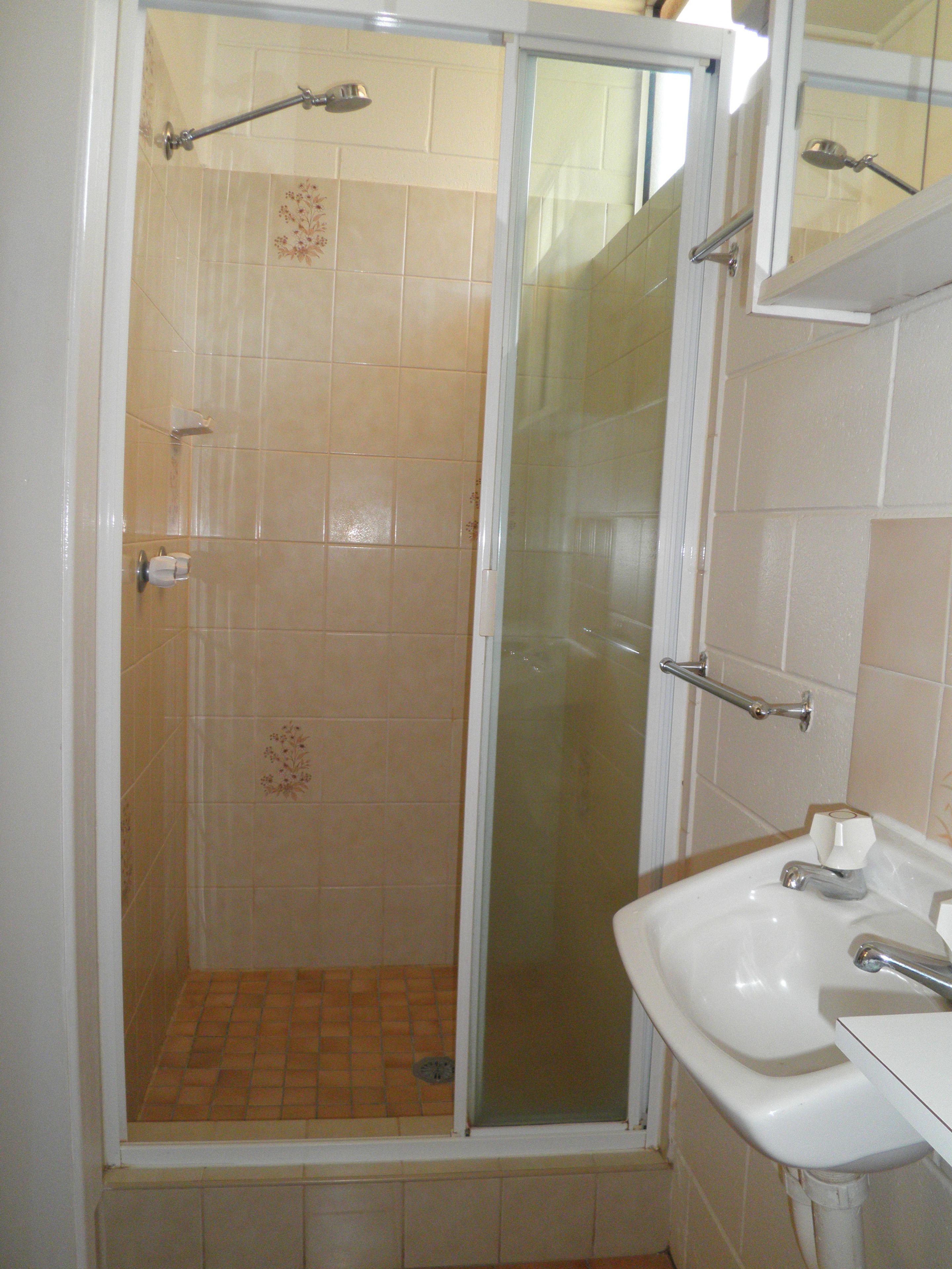 A bathroom with a glass-enclosed shower, a white sink, and a mirror above the sink.