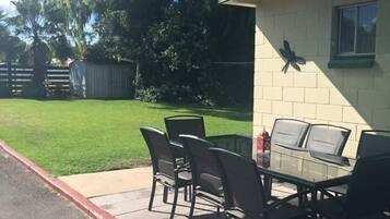 A patio with a table and chairs, a butterfly decoration on the wall, and a green canopy overhead.
