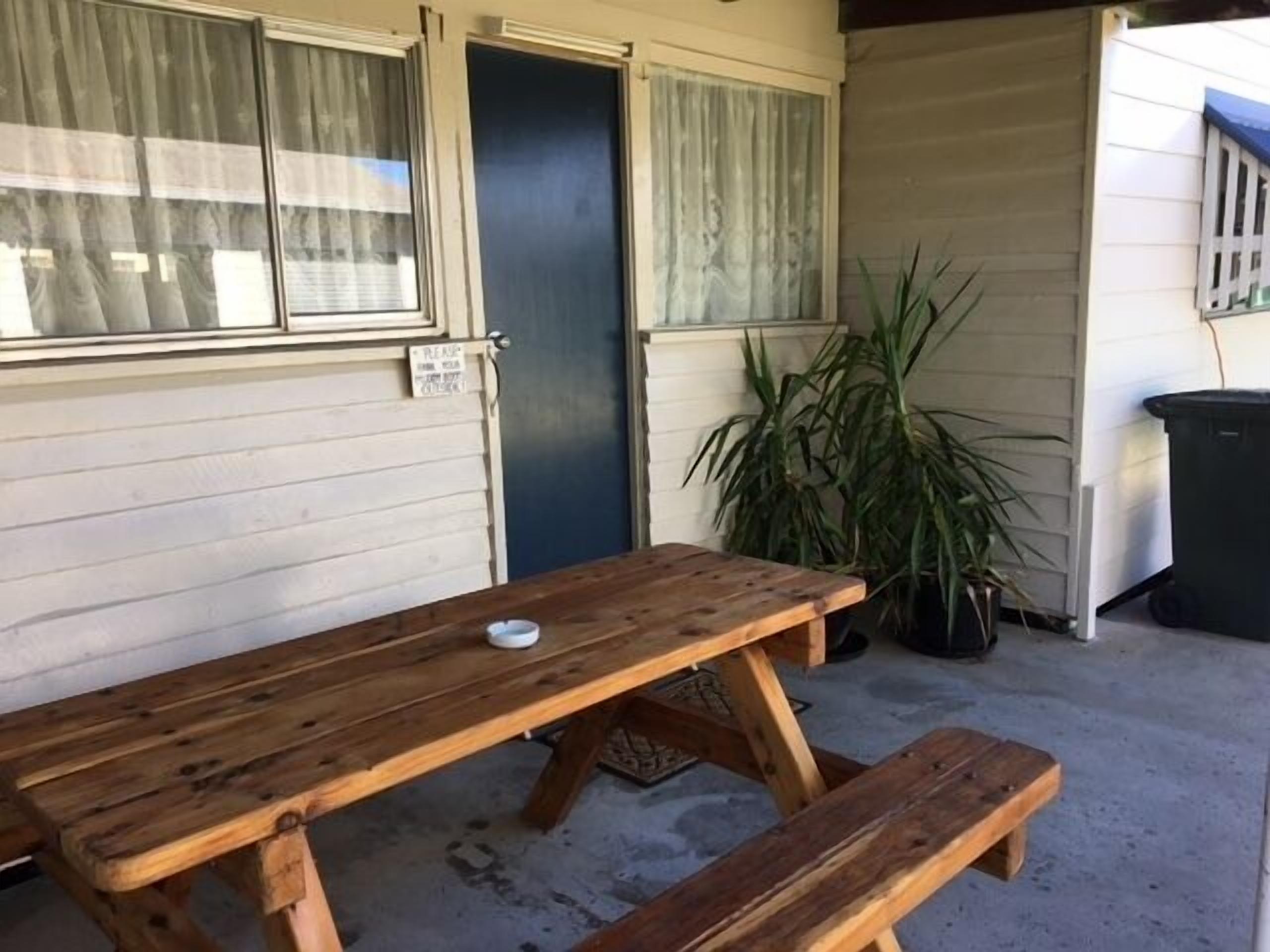 A wooden picnic table with benches in a covered outdoor area.