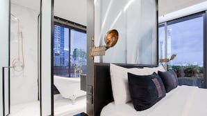 Una habitación de hotel moderna con una cama grande, una bañera y vistas a la ciudad.