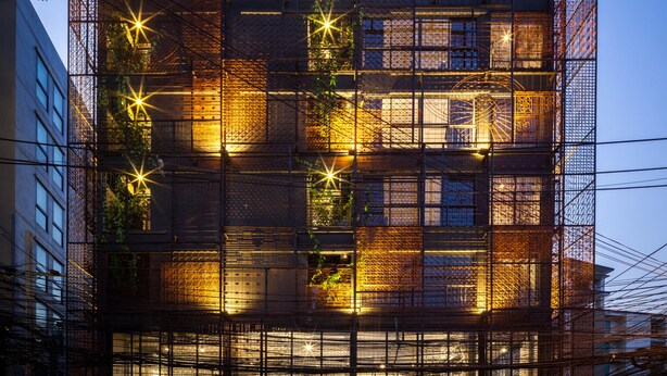 Un edificio moderno con varios pisos, amplias ventanas y un espacio al aire libre cubierto con asientos.
