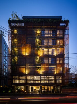 A modern building with multiple floors, large windows, and a covered outdoor area with seating. - IR-ON Hotel (Bangkok)
