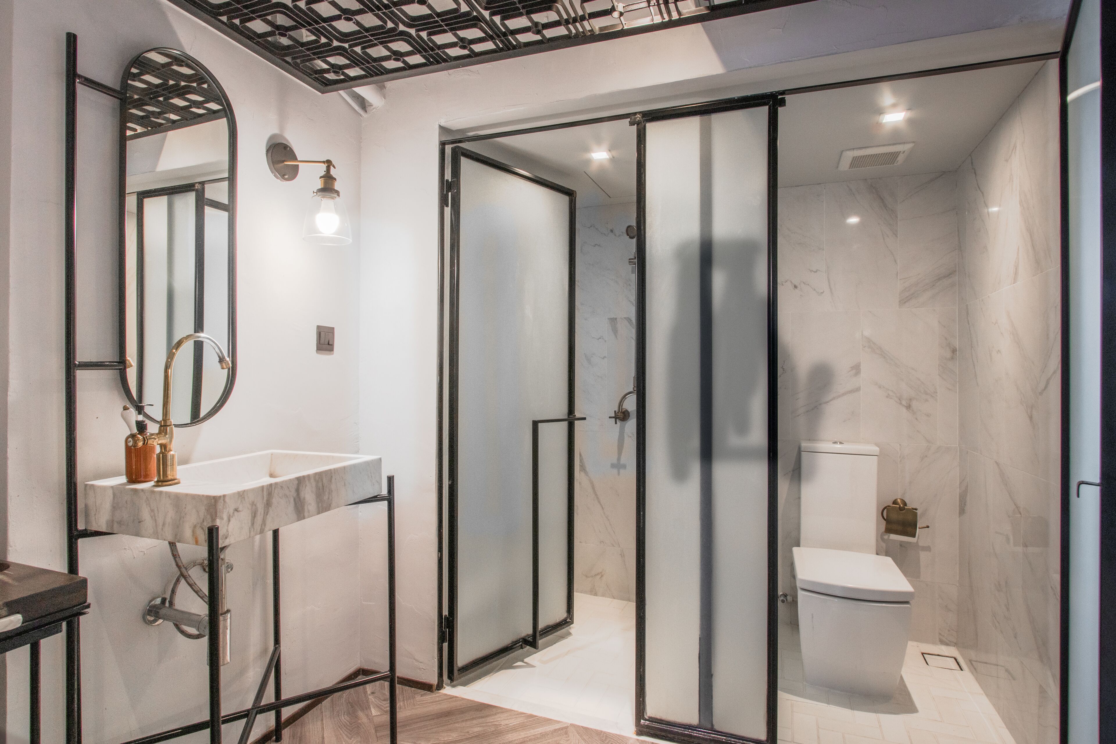 Un baño moderno con ducha envuelta en vidrio, lavamanos de mármol y un inodoro.