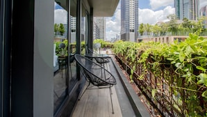 Un espacio de estar moderno al aire libre con pared de vidrio, una silla de metal y una mesa.