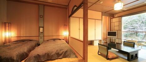 A traditional Japanese-style bedroom with a bed, bedside lamps, and a desk with a chair.