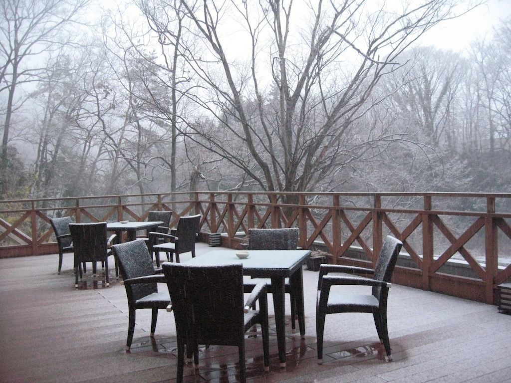 An outdoor patio with tables and chairs, surrounded by a wooden railing.