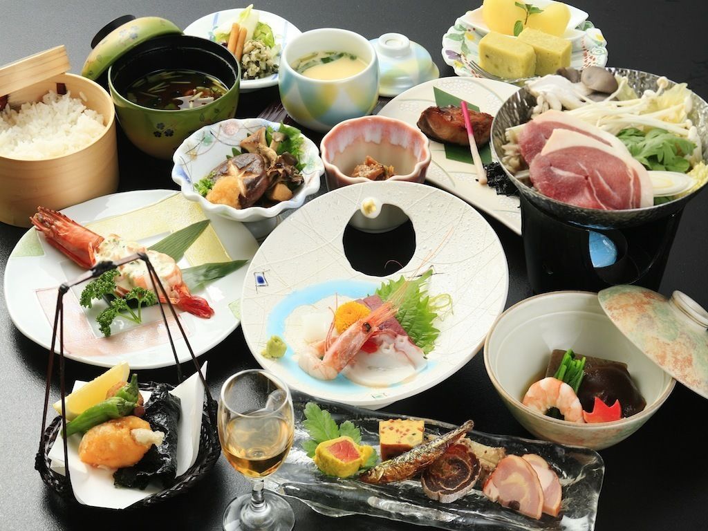 Variedad de platos japoneses, como sushi, sashimi y tempura, dispuestos sobre una mesa.