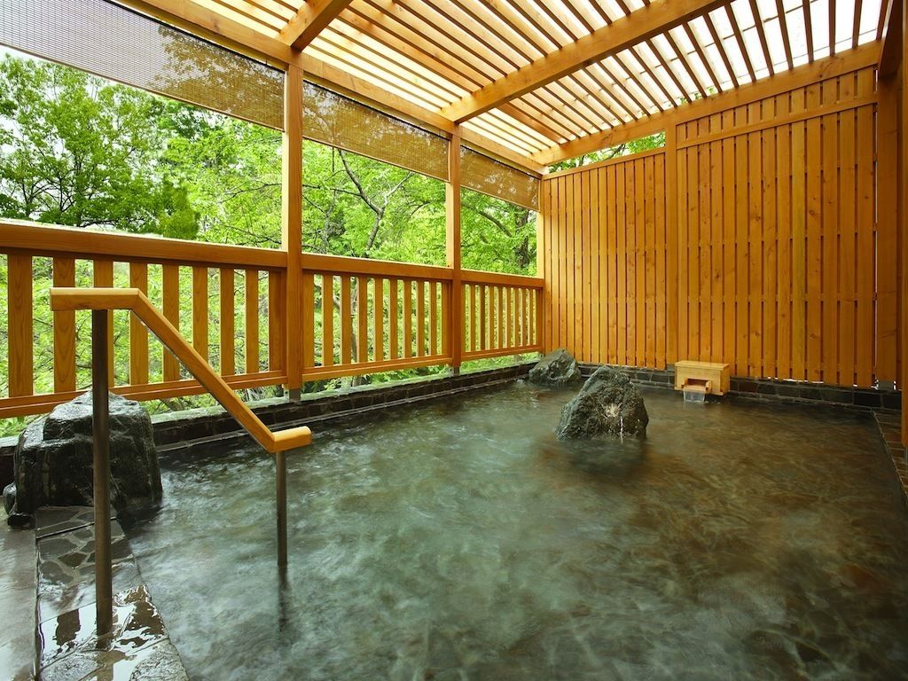 A wooden deck with a wooden fence, a stone water feature, and a bench.
