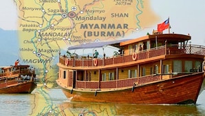 A wooden boat with a flag, passengers, and a map of Myanmar in the background. - Amara River Cruise (Mandalay)
