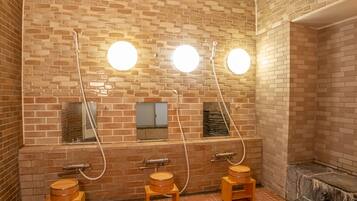 Baño público con tres lavamanos de madera, cada uno con espejo e iluminación superior.