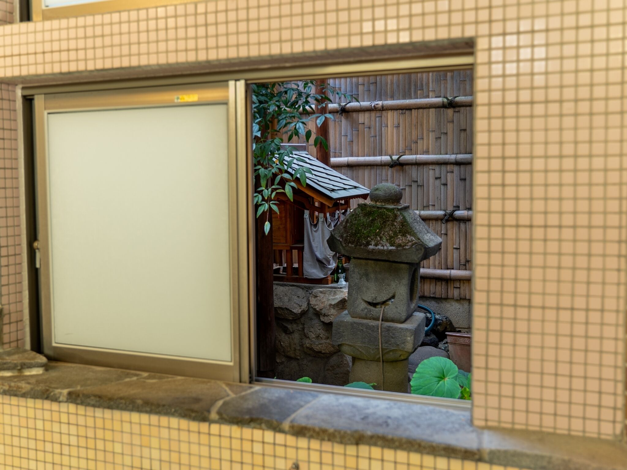 A traditional Japanese room with tatami flooring, a shoji screen door, and a stone lantern.