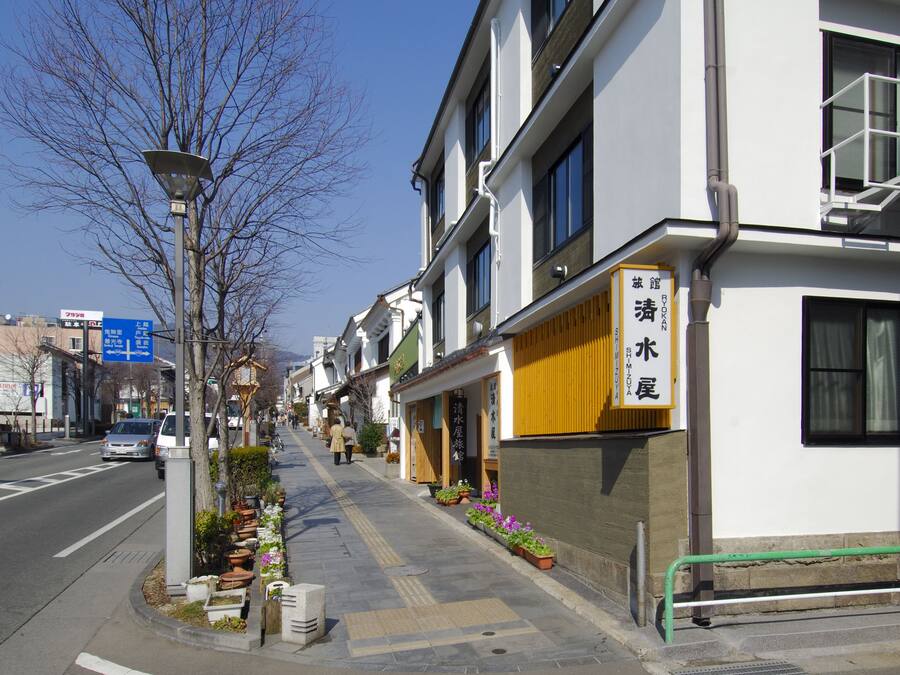 A street with buildings, a clear sky, and a sign with Japanese characters.