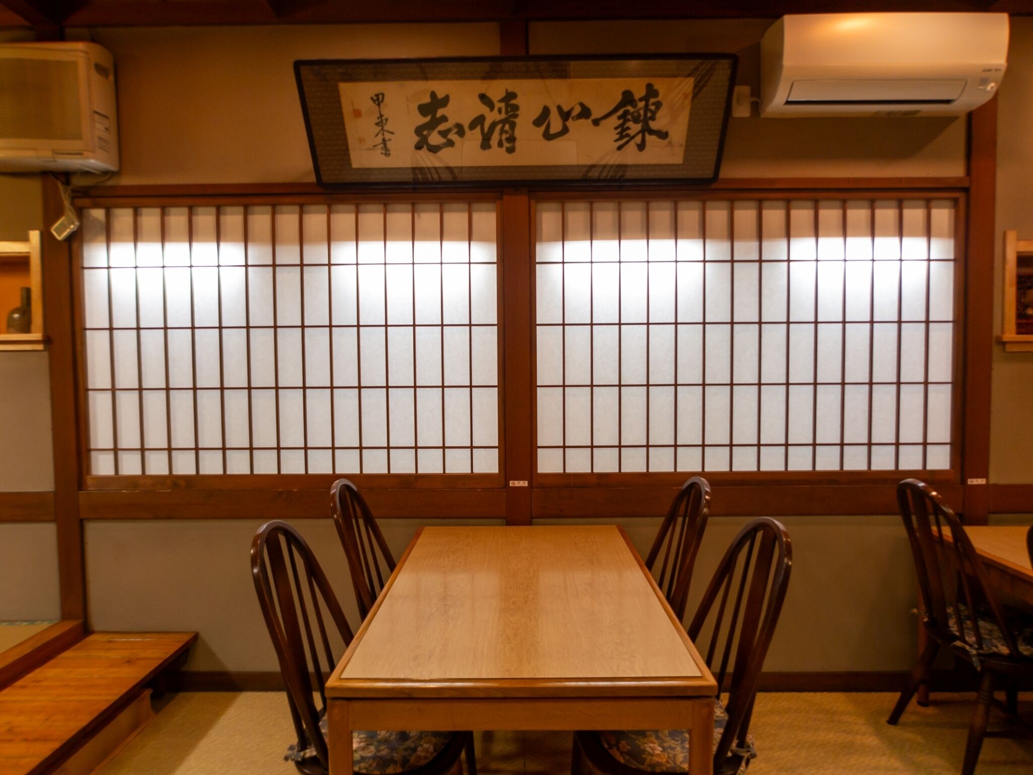 Una habitación japonesa tradicional con suelo de tatami, una mesa de madera y puertas correderas shoji.