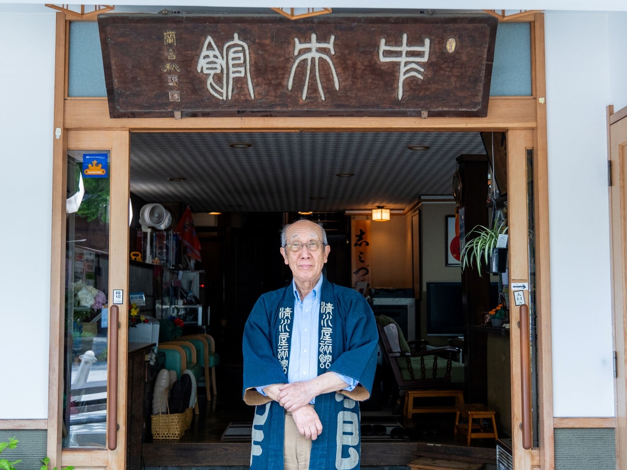 En traditionel japansk bygning med en træskilt og en person stående i indgangen.