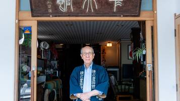 En traditionel japansk bygning med en træskilt og en person stående i indgangen.