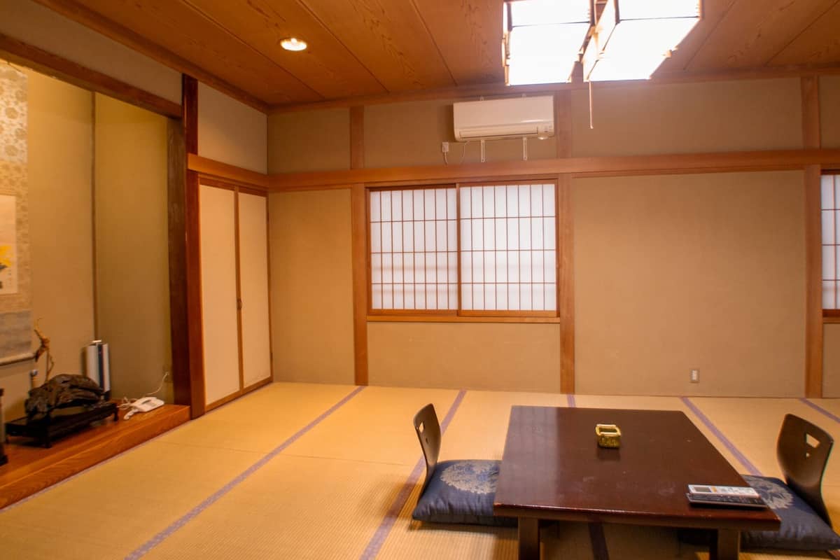Una habitación tradicional japonesa con suelo de tatami, una mesa de madera baja y puertas correderas.