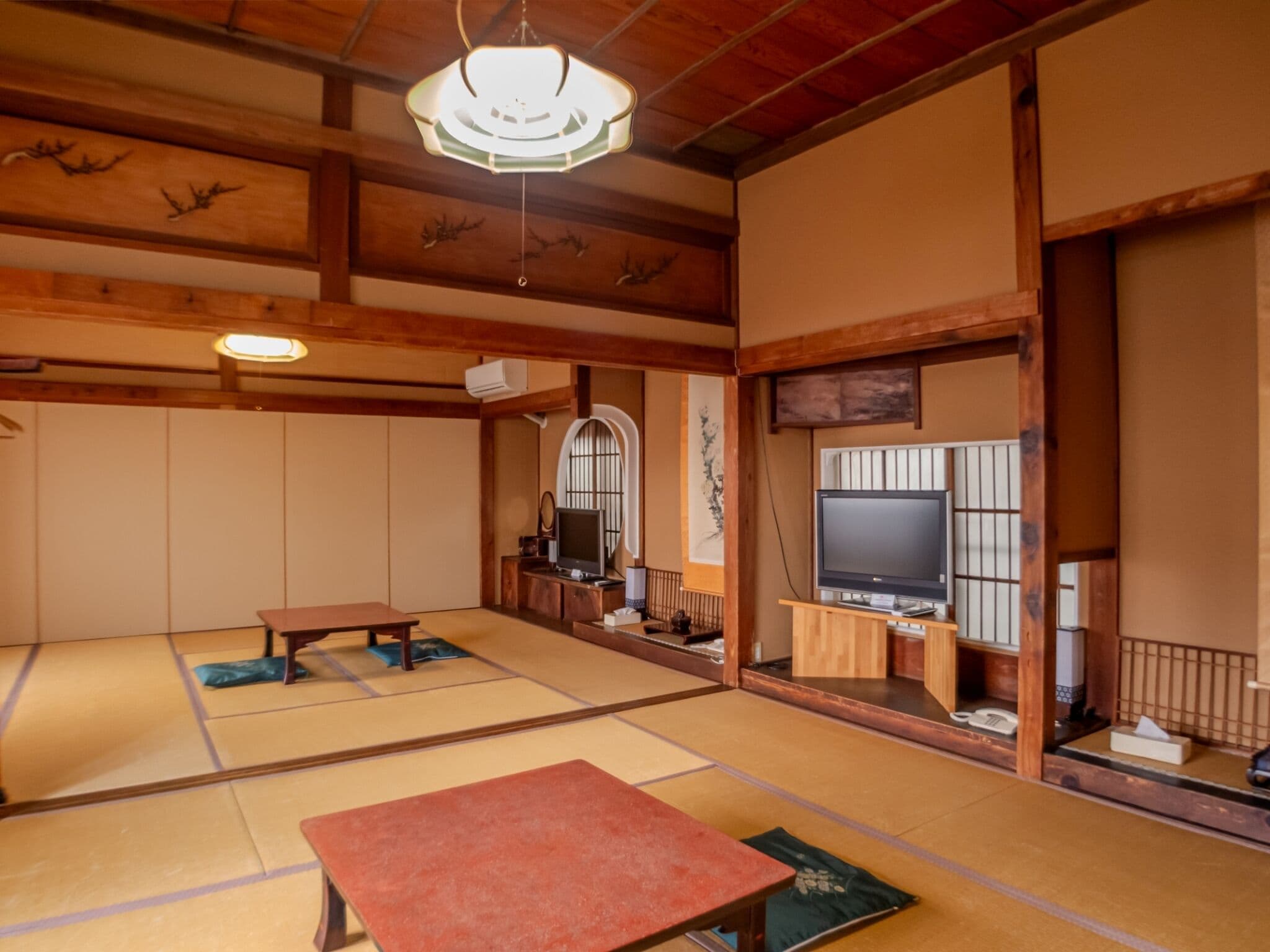 A traditional Japanese room with tatami flooring, a low table, a television, and a sliding door.