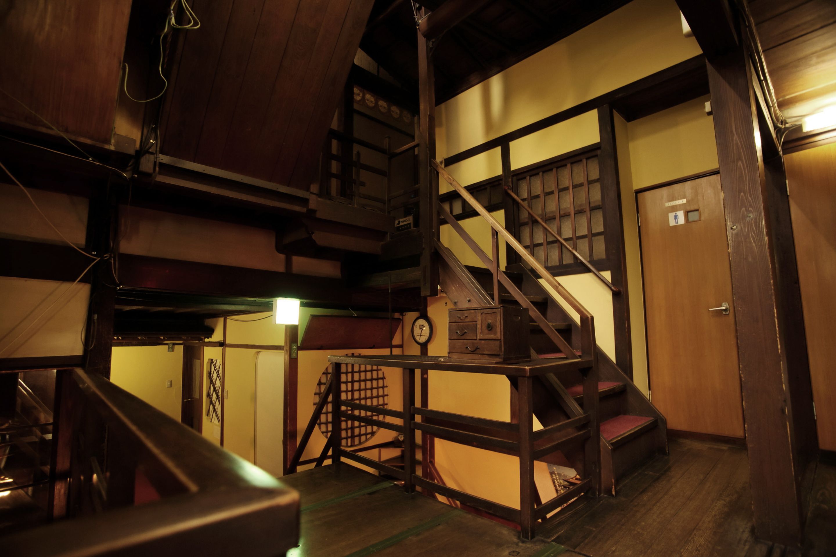 Un intérieur japonais traditionnel avec des éléments en bois, un escalier et une horloge.