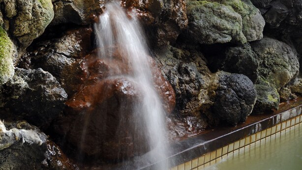 Una cascada con rocas y un borde de azulejos.