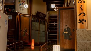 Un interior japonés tradicional con una escalera de madera, un letrero con caracteres japoneses y el logotipo de los Juegos Olímpicos de Nagano.
