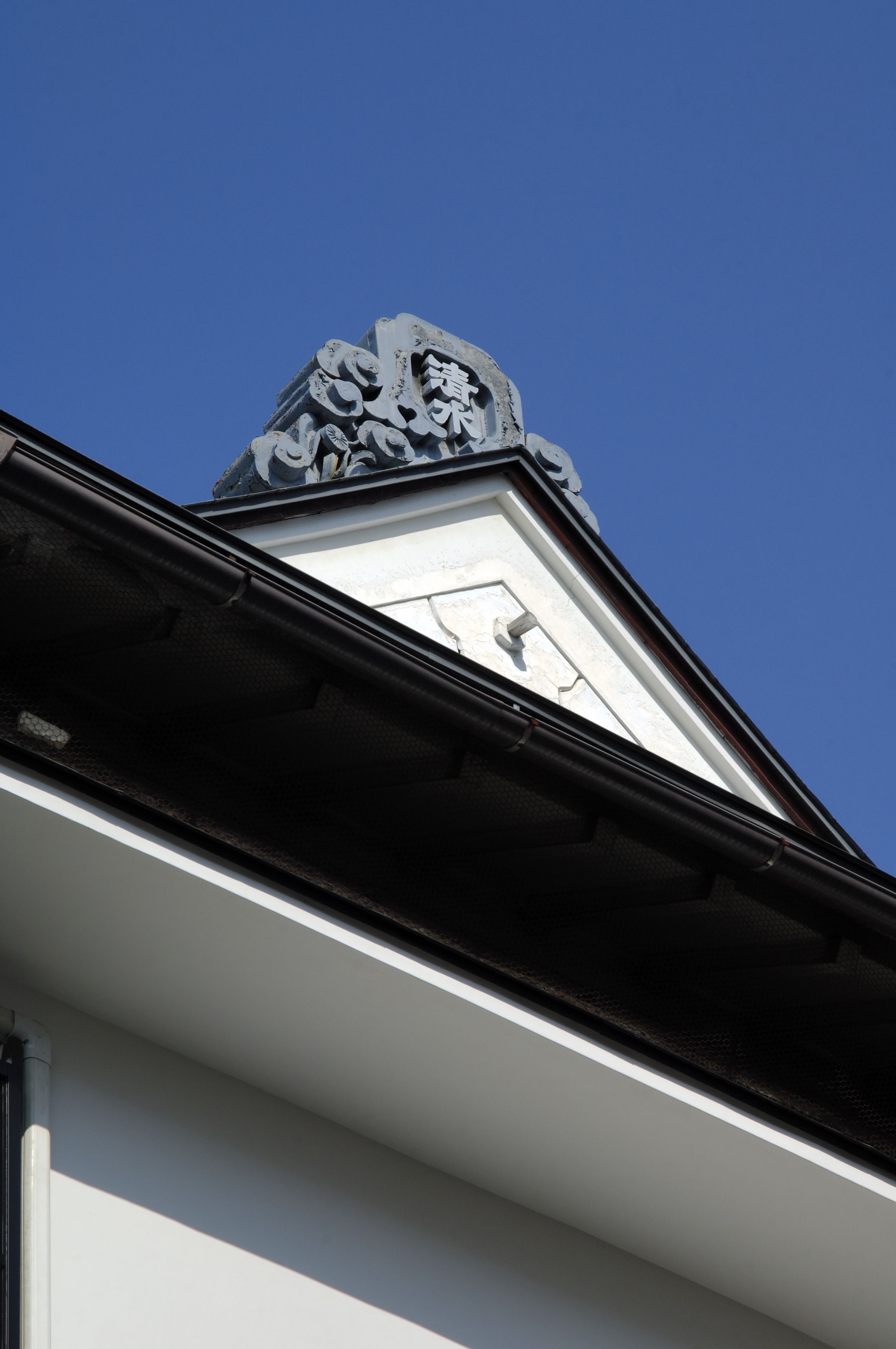 A building's corner with a white facade and a black roof edge.