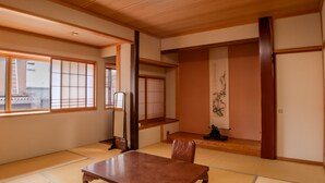 Una habitación japonesa tradicional con suelo de tatami, una mesa baja y puertas correderas.
