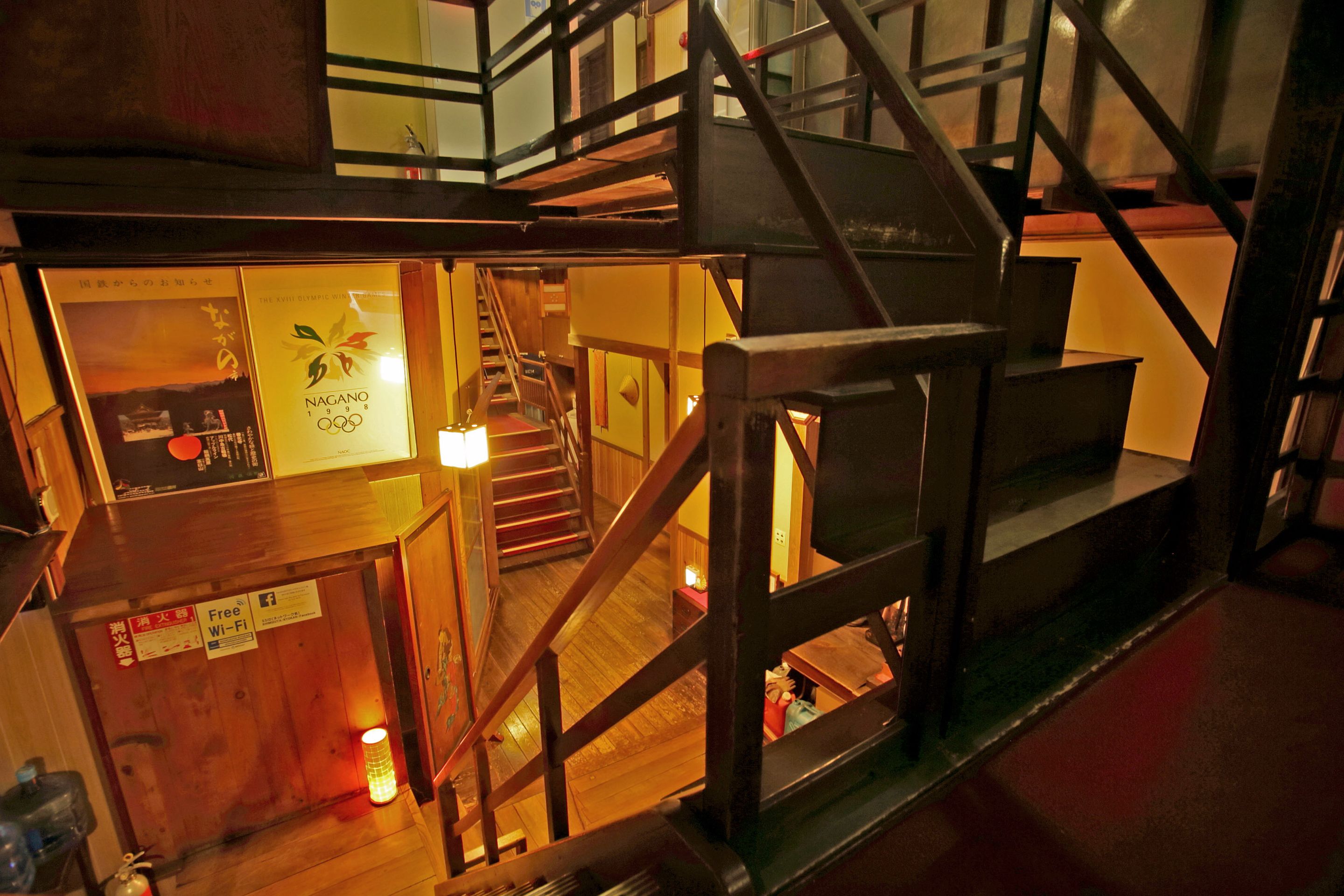 A multi-level wooden structure with a staircase, a sign indicating free Wi-Fi, and a poster with the Olympic rings.