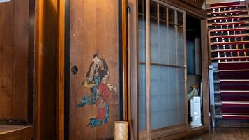 Een traditionele Japanse kamer met tatami vloerbedekking, een shoji schuifdeur en een houten glijdeur met een decoratief schilderij.
