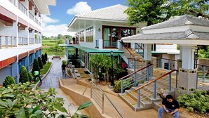 Un hotel de varios pisos con terrazas al aire libre, una escalera central y una zona de piscina.