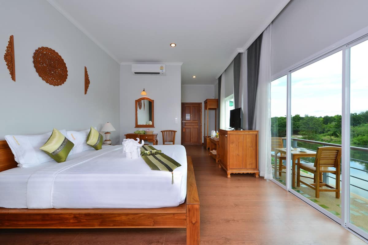 Un dormitorio espacioso con una cama grande, un aparador de madera, un televisor y un balcón con vistas al exterior.