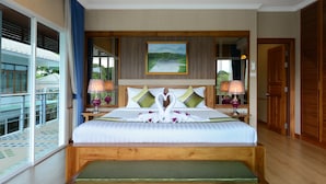Habitación de hotel con una cama grande, un banco, un cuadro en la pared y vistas al exterior.