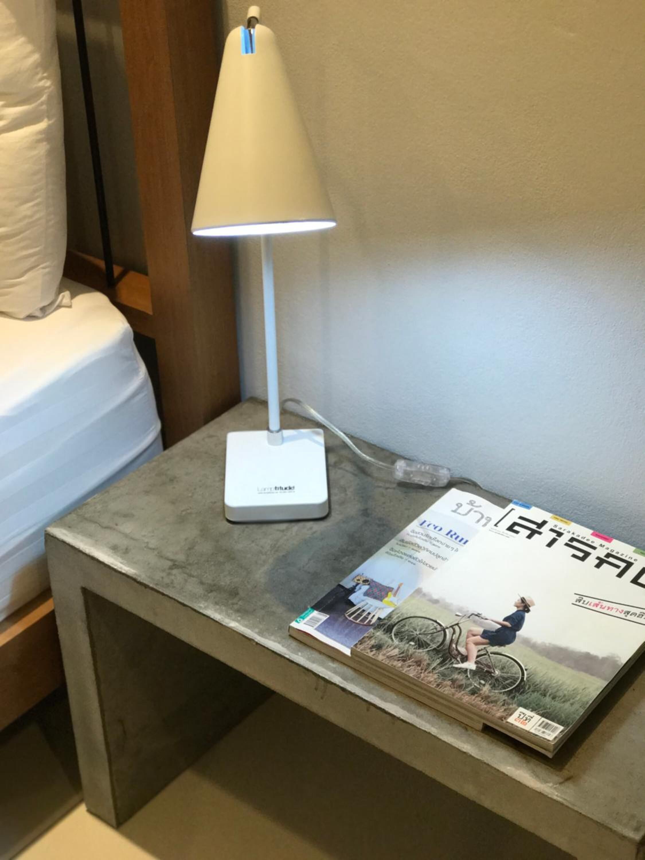 A bedside table with a lamp and a magazine.