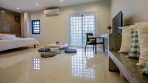 A modern hotel room with a bed, a sofa, a TV, and a window with curtains. - Little PP Hometel (Surat Thani)