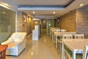 Formal dining area with a long table, comfortable seating, and a reception desk.