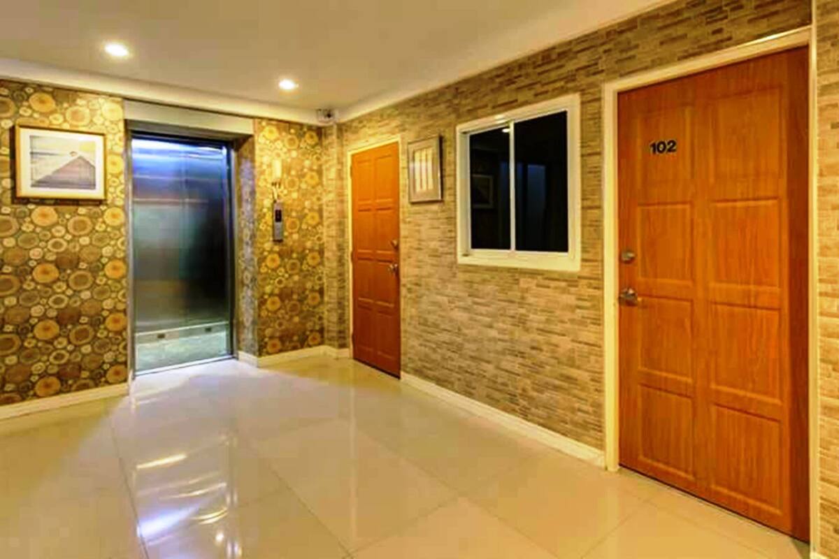 A hallway with a stone wall, a wooden door labeled 102, and a window.