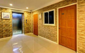 Stylish hallway with polished floors and a stone wall, featuring a framed picture and elevator access.