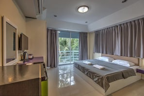 Relax in a spacious room with a large bed, flat-screen TV, and sliding glass door to a balcony with a view of palm trees.
