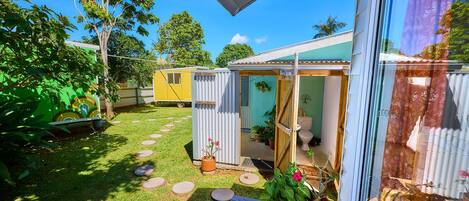 A small, enclosed outdoor area with a wooden deck, a yellow trailer, and a portable toilet.