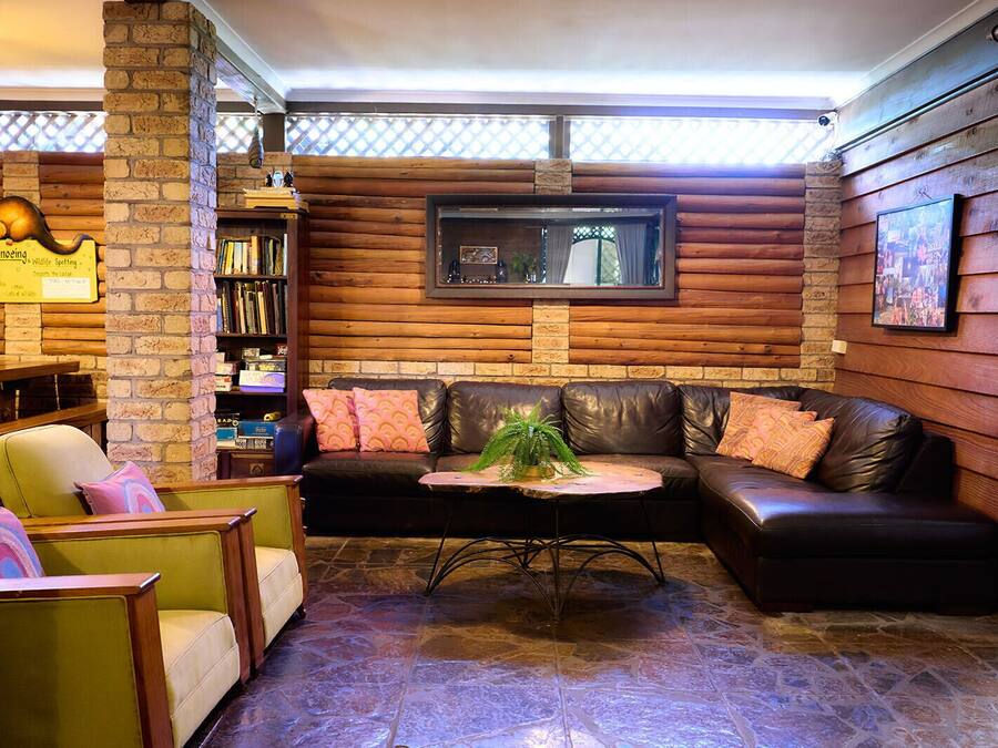 A cozy lounge area with a leather sofa, a small table with a plant, and a bookshelf filled with books.