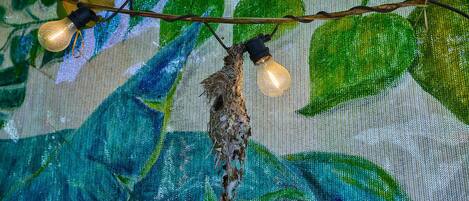 A decorative light fixture with two bulbs and a hanging ornament against a painted backdrop.