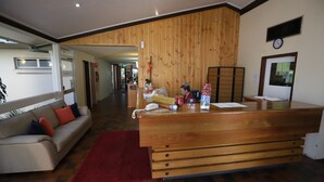 A reception area with a wooden desk, a sofa, and a red rug. - Emerald Central Hotel (Emerald)