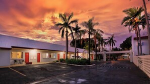 A motel with a row of rooms, a parking lot, and palm trees. - Emerald Central Hotel (Emerald)