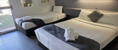 Habitación de hotel con dos camas, un ventanal grande, aire acondicionado de pared y un cuadro enmarcado.